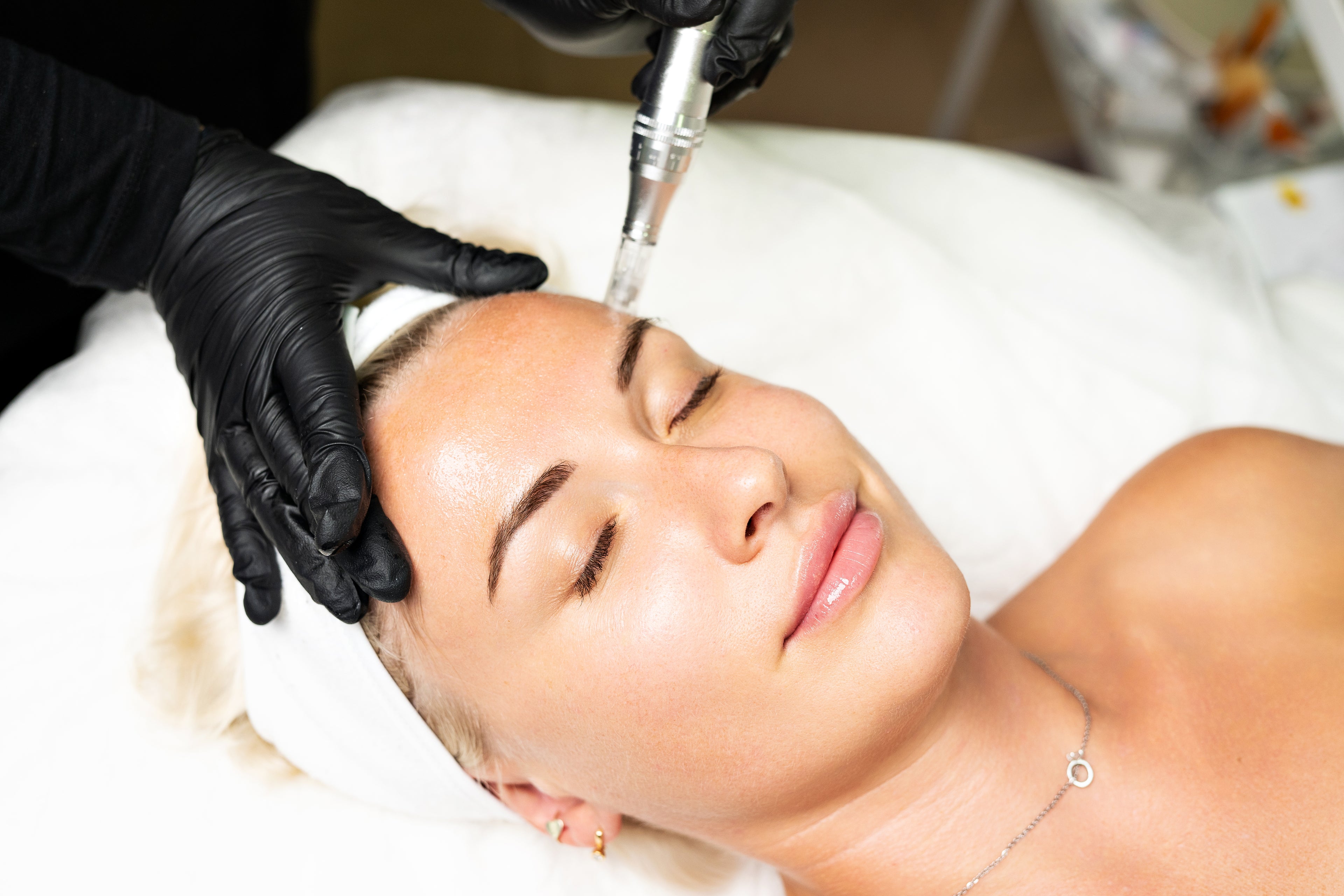 Woman receiving a facial treatment with a tool held by a gloved hand.