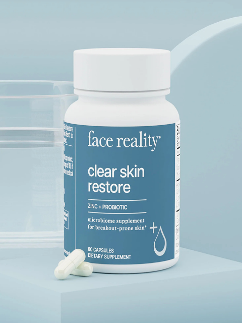 Supplement bottle labeled 'face reality clear skin restore' on a light blue background