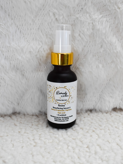 Skincare serum bottle with gold cap on a textured white background